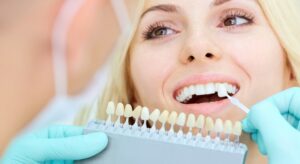 Woman smiling while a dentist holding up samples to match her tooth color
